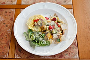 White plate with fried mushrooms and vegetables, boiled rice and fresh spinach. on a wooden table top decorated with ceramic tiles