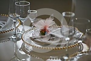 White plate with a golden edge, glasses and cutlery on a table