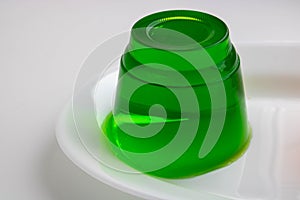 White plate with green kiwi jelly on a white background