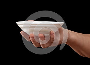 White plate in hand on a black