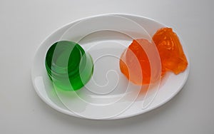 White plate with kiwi and orange jelly on a white background