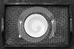 White plate, knife and fork at napkin on wooden