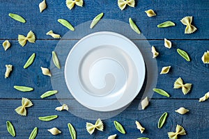 White plate with mix of different pastas on wooden background