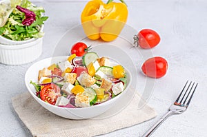 White plate with mix vegetable salad, greens, crackers and sesame seeds on a light background