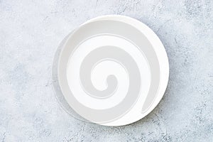 White plate and napkin at stone table.