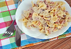 White plate of pasta carbonara with ham