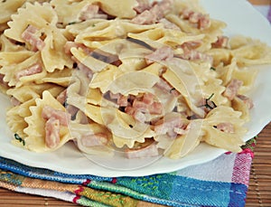 White plate of pasta carbonara with ham