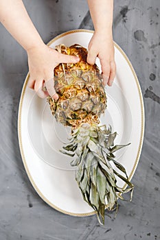 White Plate with Ripe Whole Pineapple on Grey Concrete Background