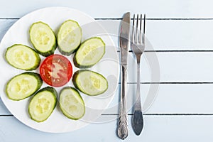 White plate with salad from tomato and cucumber. Vegetarian breakfast or lunch. Top view on wooden table with copy space