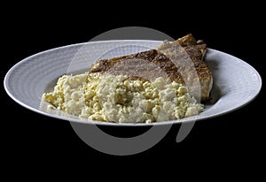 A white plate with scrambled egg and a salmon steak