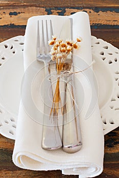 White plate serviette fork knife dried flowers