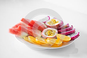 White plate of sliced fruit. Fresh fruits and vitamins. Still life colored summer fruits