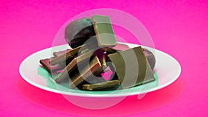 White plate with snack onpink background