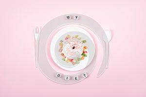 White plate with spoon, fork and Donut decorated icing and sprinkles. Unhealthy Junk Food. Dieting, Healthy Eating, Lifestyle.