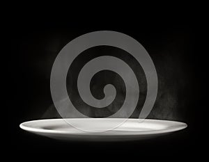 White plate with steam on black background