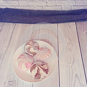 White plate with tasty marshmallows stand on a wooden table