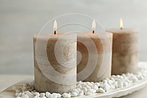 White plate with three burning candles and rocks