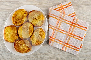 White plate with toasted slices of bread, napkin on wooden table. Top view