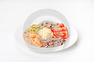 White plate with tomatoes, cucumbers, mushrooms and meat.