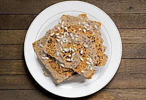 White plate with vegan dry raw bread loaves on wooden table