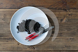 White plate on a wooden background with seaweed of the genus Codium fragile