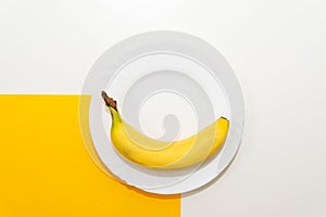 White plate with yellow banana. Yellow color.