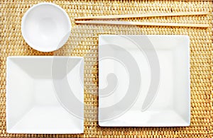 White Plates and Chopsticks on a Bamboo Mat