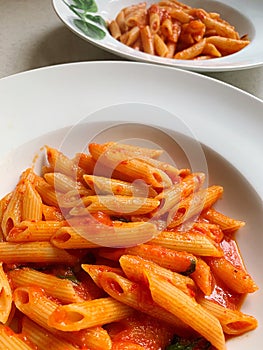 White plates with penne pasta in tomato sauce, classic Italian dish, carbohydrate dish, fresh tomato sauce