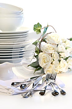 White plates stacked with utensils and roses