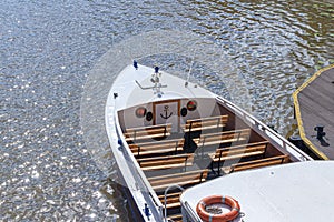 White pleasure boat with benches for passengers, at the river pier