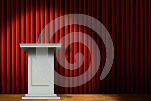 White podium on stage under spotlight over red curtain