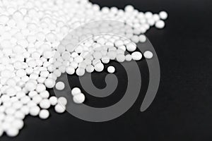 White Polystyrene foam beads on black background with copy space, waste cushioning material in luxury packaging