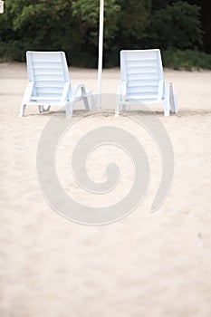 White pool chairs on sand beach