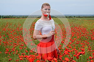 White poppy flower in the hands of a girl in the middle of a field of red poppies