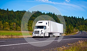 White popular luxe semi truck trailer on scenic highway