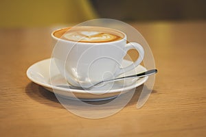 White porcelain cup of coffee with a saucer and a spoon