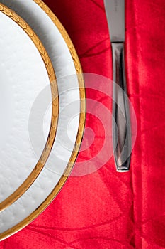 white porcelain dish with golden relief with decorations on a red table. luxury plates and dishes used for celebrations. porcelain
