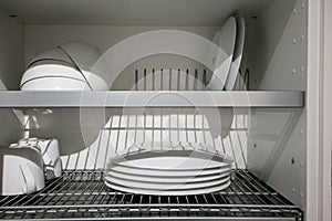 White porcelain dishes dried on metal dish rack. Way to organize