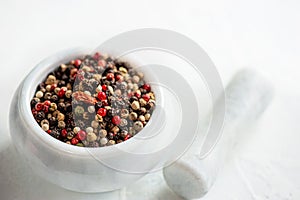 White porcelain mortar and pestle with hot red chili pepper and different types of peppers. Peppers are prepared for grinding and