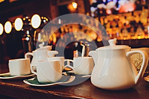 White porcelain tea set-folded cups and saucers and teapot. Tea ceremony tableware on a dark background.