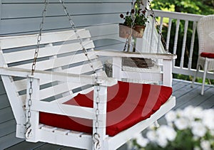 White porch swing with red cushions