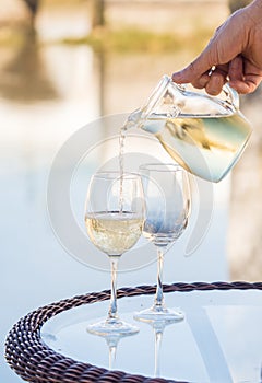 White Portuguee wine poured to glasses on an outdoor table by the river in Tavira, Portugal