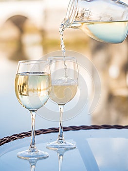 White Portuguee wine poured to glasses on an outdoor table by the river in Tavira, Portugal