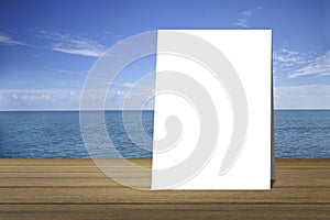 White poster put on wood table and beautiful peace sea in background. product display template. Business presentation.