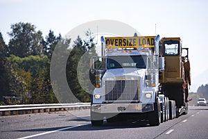 Big rig semi truck with oversize load sign and step down trailer photo