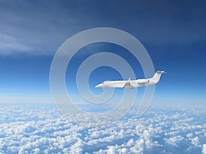 White private jet business jet flies against backdrop of beautiful white clouds on blue sky