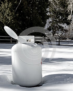 White propane tank in winter with lid open for maintenance