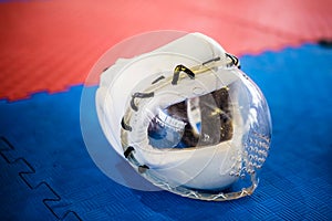 White protective helmets with clear plactic mask for martial arts on the red blue floor