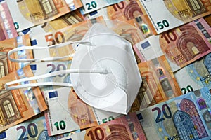 White protective medical face mask laying on the European union money currency Euro