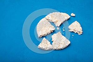 White puffed rice snack with crumbs on blue rustic background